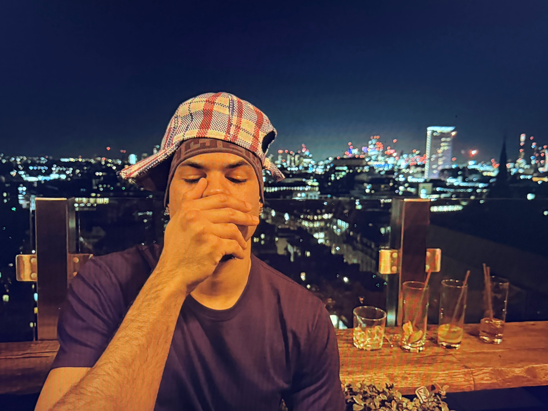 Jaywakeup at a rooftop table at night with the illuminated city skyline behind him